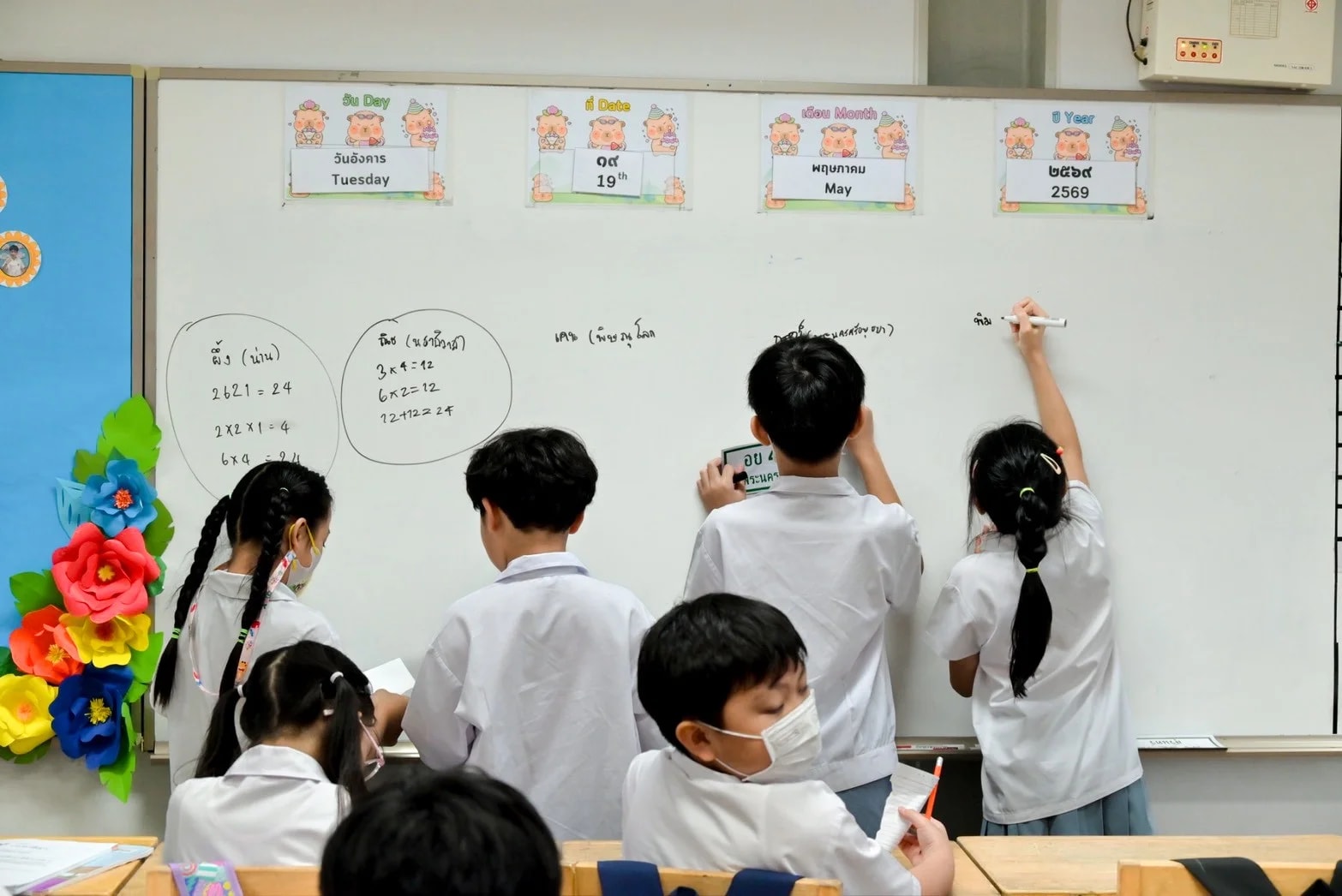 Plookpanya primary students solving maths problems together at the whiteboard, representing academic excellence